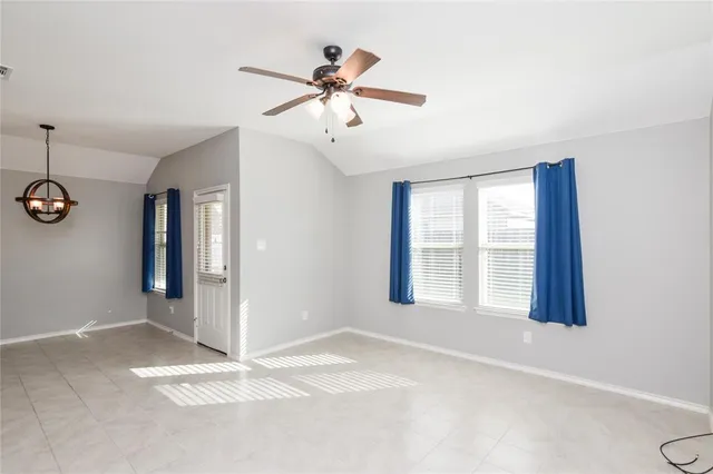 a view of an empty room with window and chandelier fan