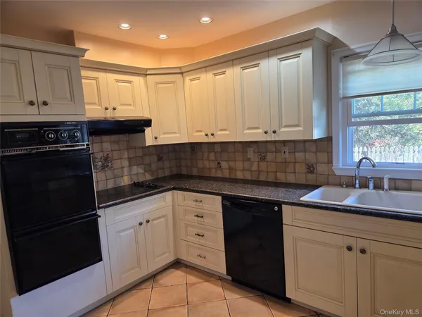 a kitchen with granite countertop white cabinets and black appliances