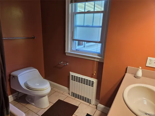a white toilet sitting next to a bathroom sink and a window