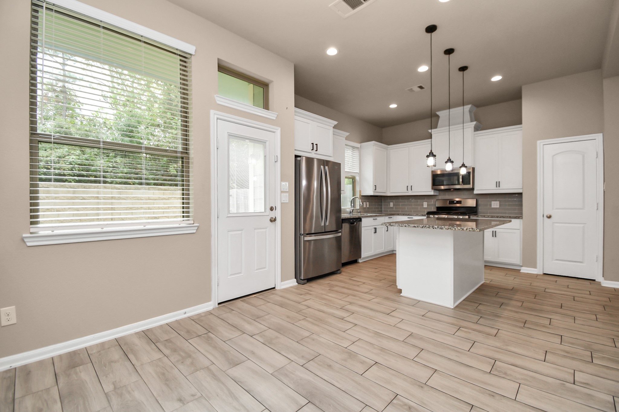 4220 Merry Mill Drive Spring, TX 77386 - Photo 14 of 44 a kitchen with stainless steel appliances kitchen island granite countertop a refrigerator a sink dishwasher a stove and white cabinets with wooden floor