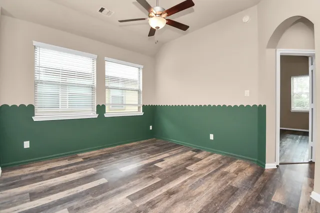 a view of an empty room with a window and wooden floor