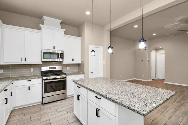 a large kitchen with stainless steel appliances granite countertop a stove a sink and a refrigerator