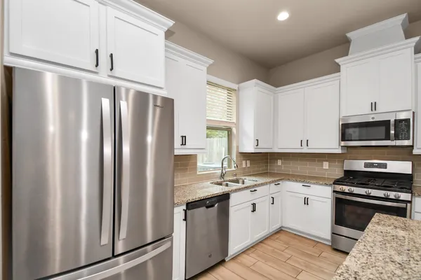 a large kitchen with stainless steel appliances granite countertop a refrigerator and a sink