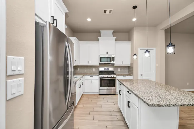 a view of an empty room with kitchen and window