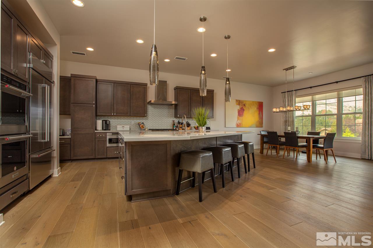 4105 Whispering Pine Loop Reno, NV 89519 - Photo 6 of 35 a kitchen with stainless steel appliances granite countertop a refrigerator a stove a sink a dining table and chairs with wooden floor
