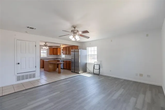 a living room with couches and kitchen view with wooden floor