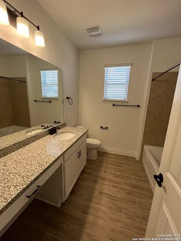 a bathroom with a granite countertop sink toilet and shower