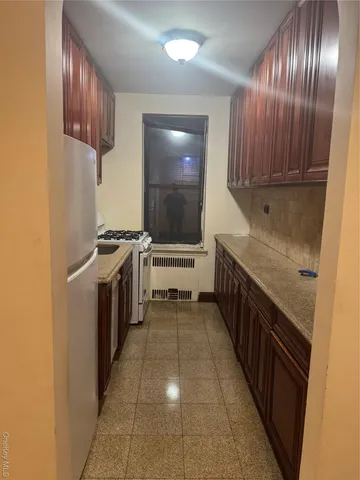 a kitchen with granite countertop a stove a sink and a refrigerator