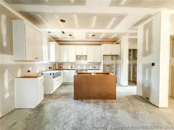 a large white kitchen with kitchen island a counter top space a sink stainless steel appliances and cabinets