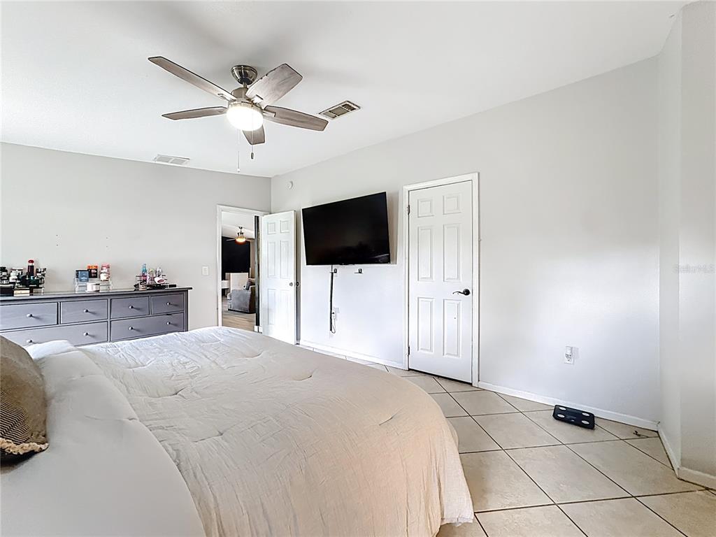 18604 Belvedere Road Orlando, FL 32820 - Photo 22 of 50 a large bedroom with a bed and a flat screen tv