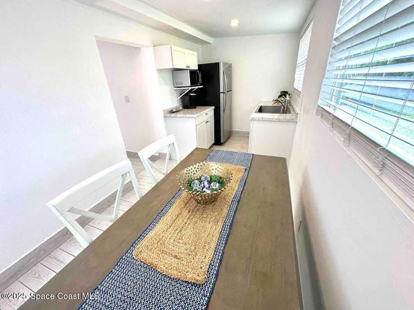 a living room with stainless steel appliances furniture a rug and a window