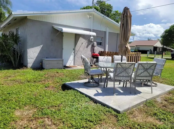 a view of a patio with table and chairs potted plants and a large tree