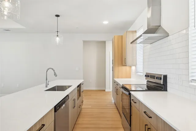 a kitchen with a sink dishwasher a stove and a refrigerator with wooden floor