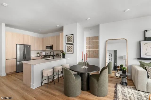 a kitchen with stainless steel appliances kitchen island granite countertop a stove a refrigerator a sink a dining table and chairs with wooden floor