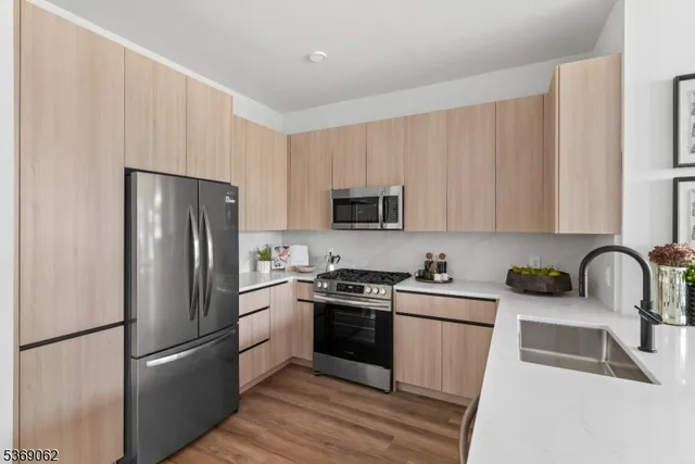 a kitchen with stainless steel appliances granite countertop a refrigerator stove a sink and dishwasher with wooden floor