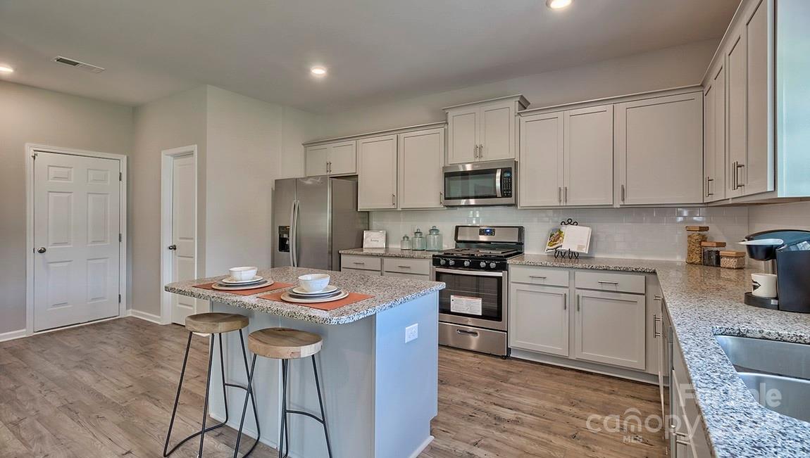 4025 Cramer Estates Gastonia, NC 28056 - Photo 17 of 36 a kitchen with stainless steel appliances kitchen island granite countertop a sink a stove a refrigerator and island