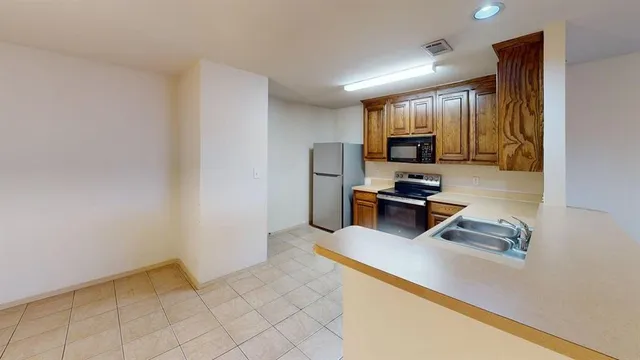 a kitchen with granite countertop a sink cabinets and stainless steel appliances