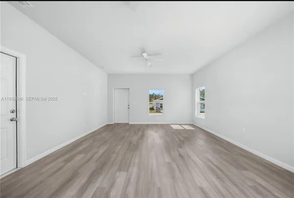 an empty room with wooden floor and windows