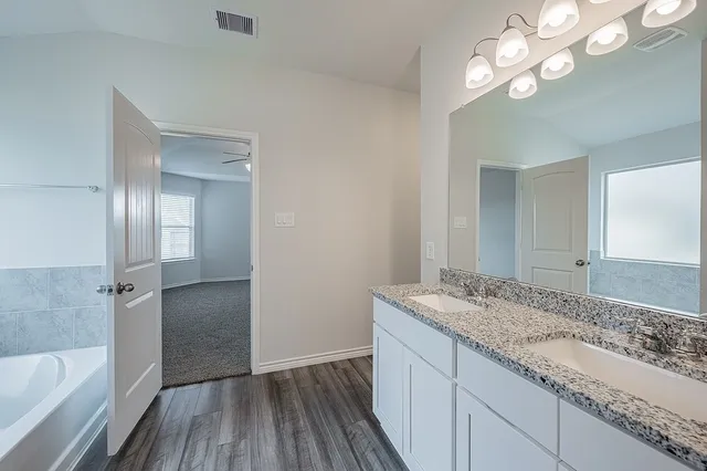 a bathroom with a granite countertop sink a light fixture and a mirror