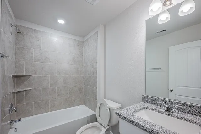 a bathroom with a granite countertop sink mirror toilet and bathtub
