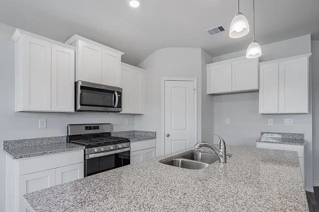 a kitchen with stainless steel appliances granite countertop a sink a stove and a microwave