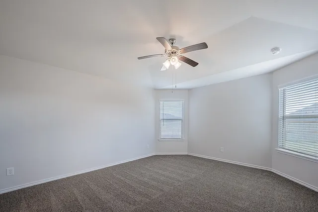 an empty room with windows and fan