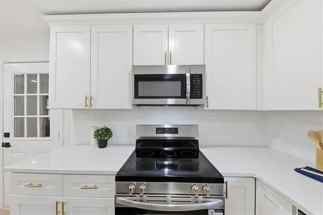 a kitchen with stainless steel appliances granite countertop white cabinets a stove a sink and dishwasher