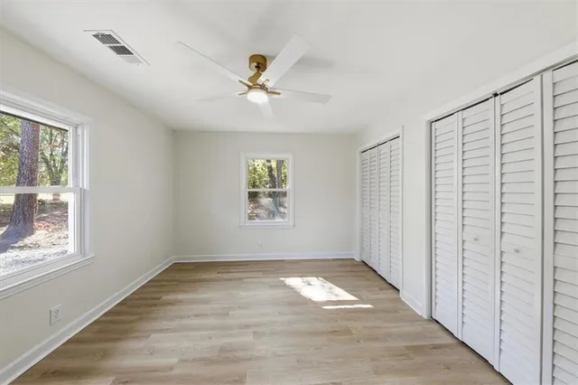 a view of empty room with wooden floor and fan