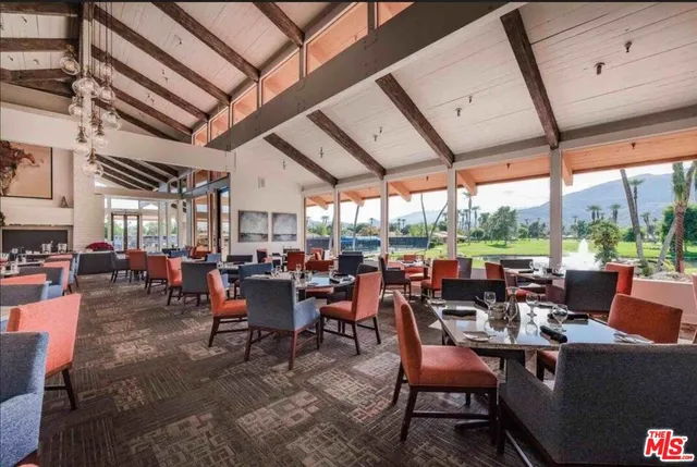 a room with lots of tables a large window and chairs