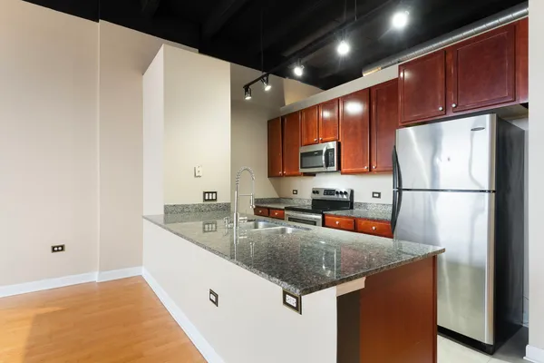 a kitchen with stainless steel appliances granite countertop a refrigerator a sink dishwasher a stove with wooden cabinets