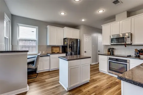 a kitchen with white cabinets and stainless steel appliances