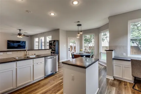 a kitchen with granite countertop a sink cabinets and wooden floor