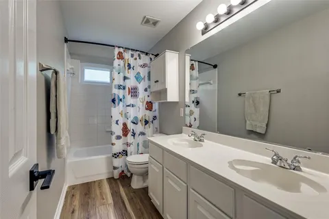 a bathroom with a double vanity sink toilet mirror and shower