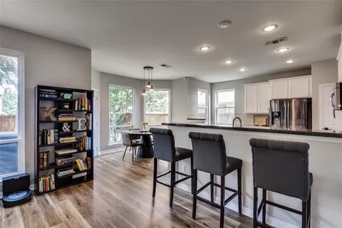 a kitchen with stainless steel appliances granite countertop a stove a refrigerator a table and chairs with wooden floor