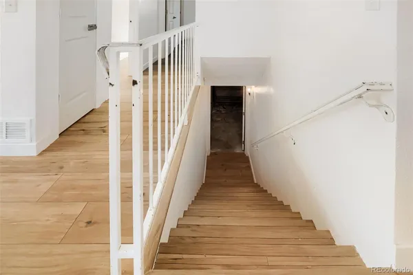 a view of a hallway with wooden floor and staircase