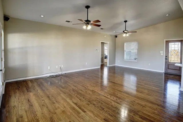 an empty room with wooden floor and windows