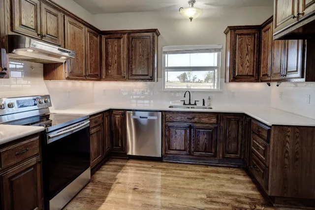 a kitchen with stainless steel appliances granite countertop a sink stove and cabinets
