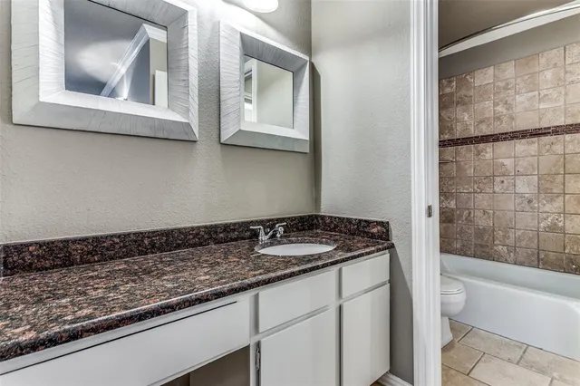 a bathroom with a granite countertop sink and mirror with bathtub