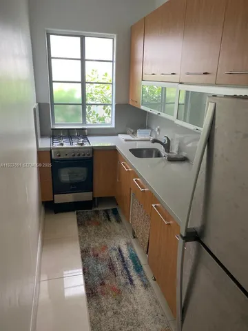 a kitchen with granite countertop a sink a stove and a refrigerator
