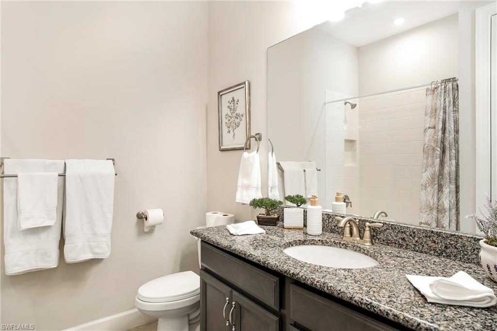 8131 Lucello Terrace North Naples, FL 34114 - Photo 22 of 32 a bathroom with a granite countertop sink a toilet a mirror and shower