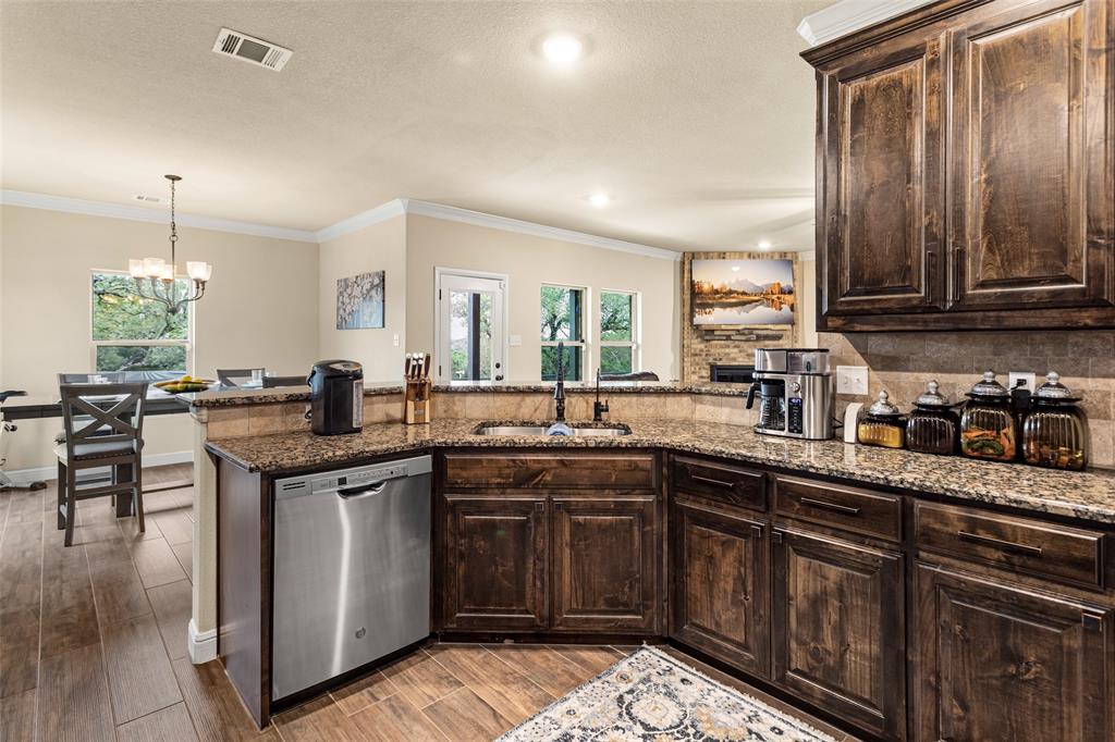 223 Cottongame Road Weatherford, TX 76088 - Photo 13 of 39 a kitchen with stainless steel appliances granite countertop a stove a sink dishwasher and cabinets with wooden floor