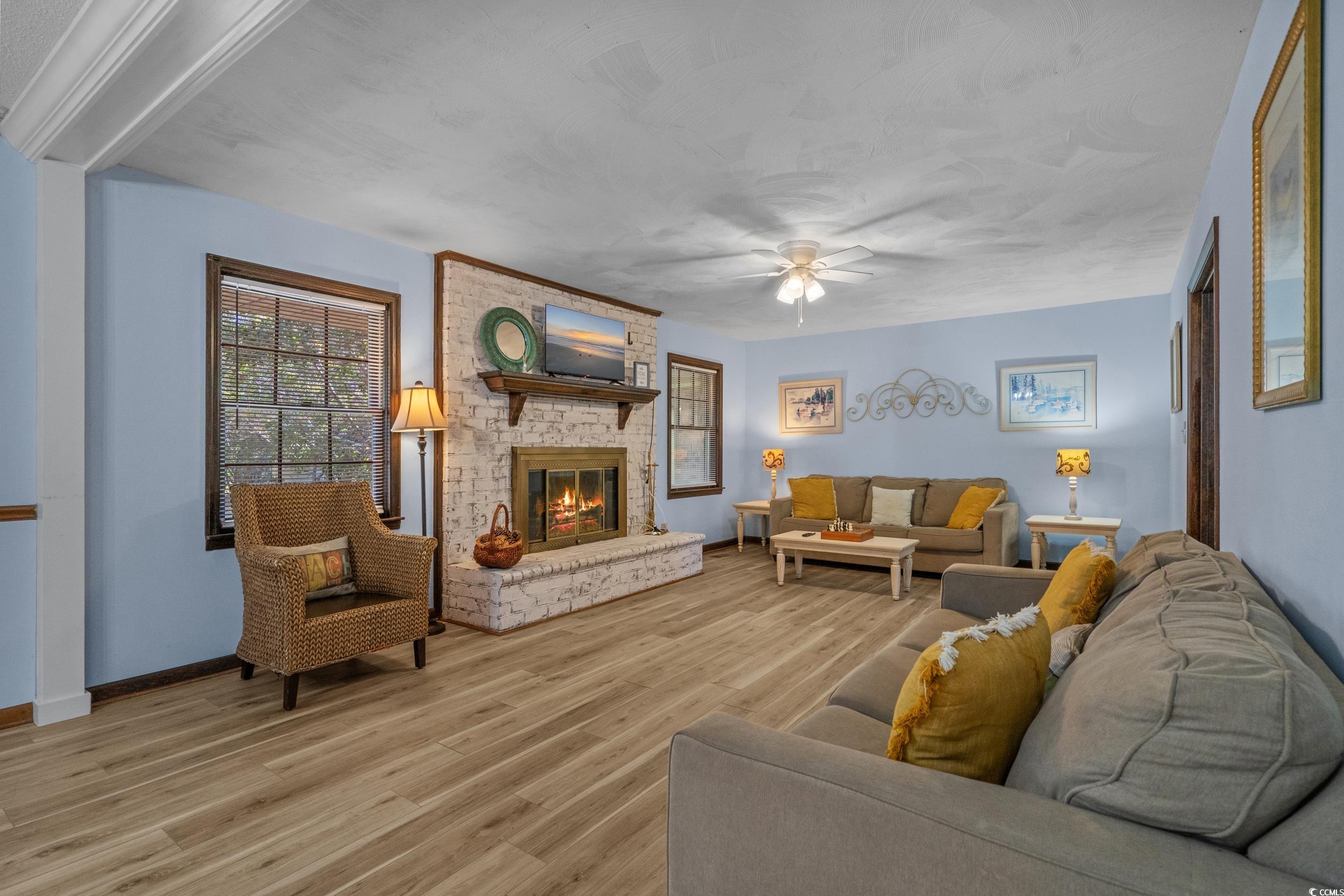 1063 Burcale Road Myrtle Beach, SC 29579 - Photo 13 of 36 Living room with light wood-style flooring, a ceiling fan, and a brick fireplace