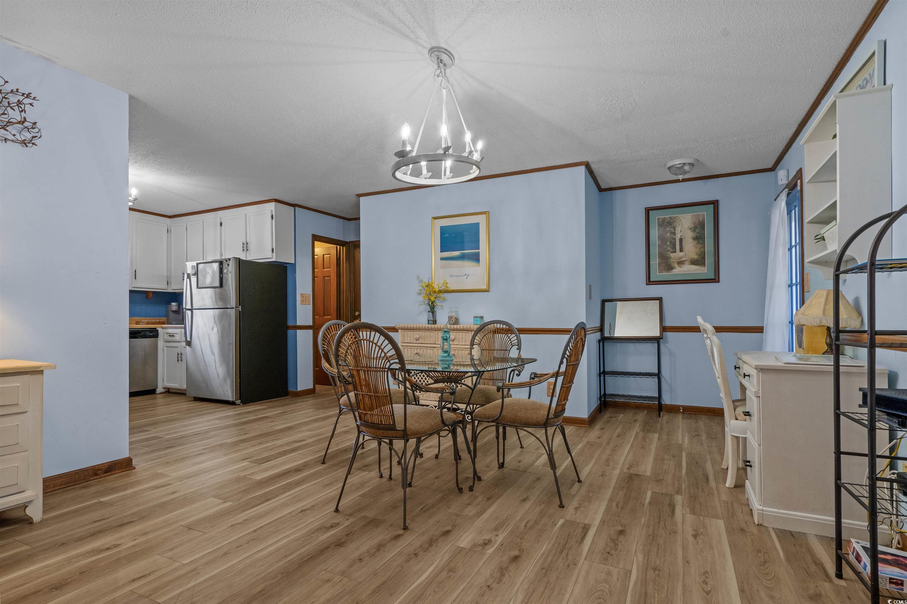 1063 Burcale Road Myrtle Beach, SC 29579 - Photo 14 of 36 Dining area featuring light wood-type flooring, ornamental molding, a textured ceiling, and a chandelier