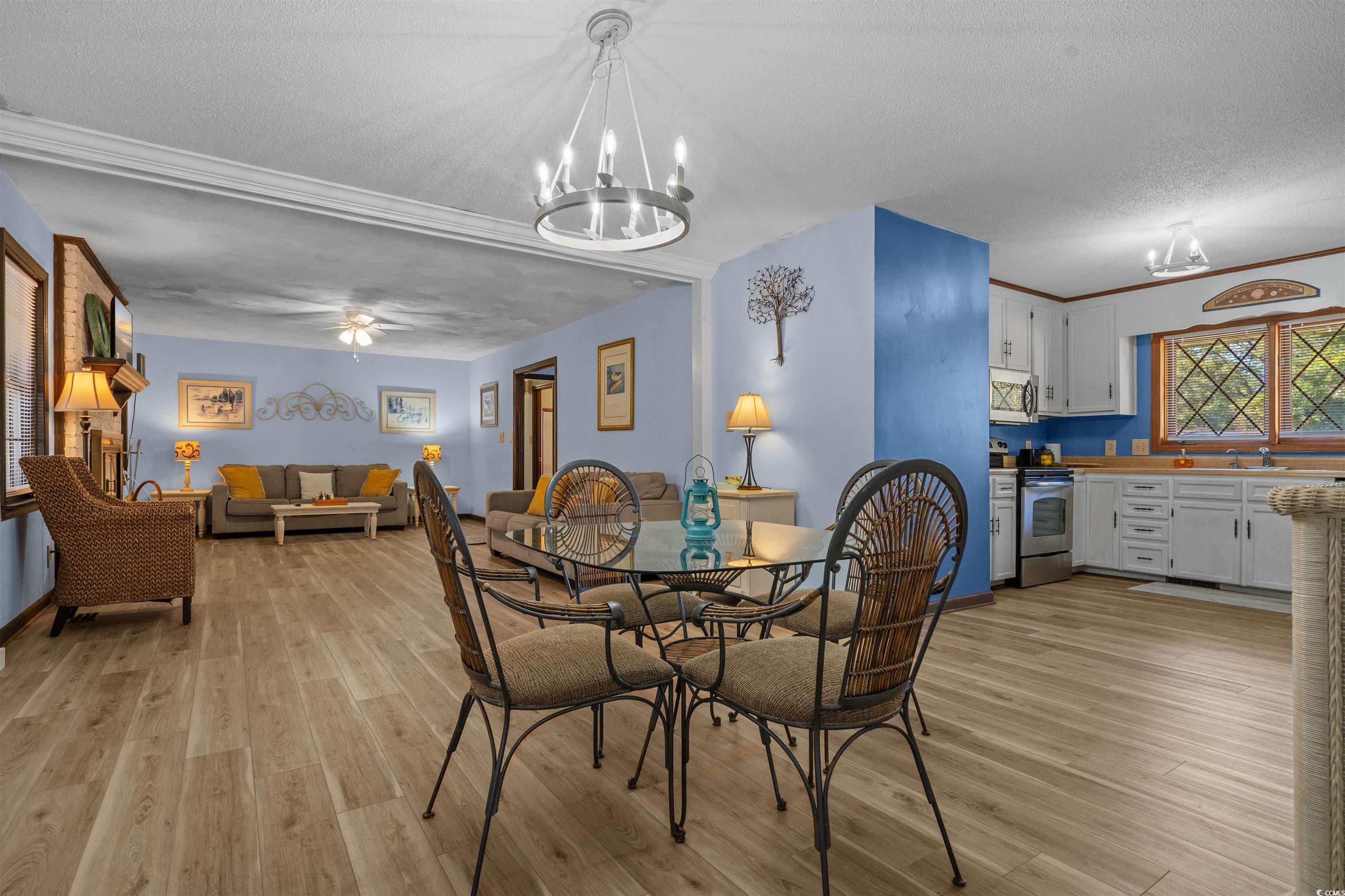 1063 Burcale Road Myrtle Beach, SC 29579 - Photo 15 of 36 Dining space featuring a chandelier, a textured ceiling, light wood-style flooring, ceiling fan, and ornamental molding