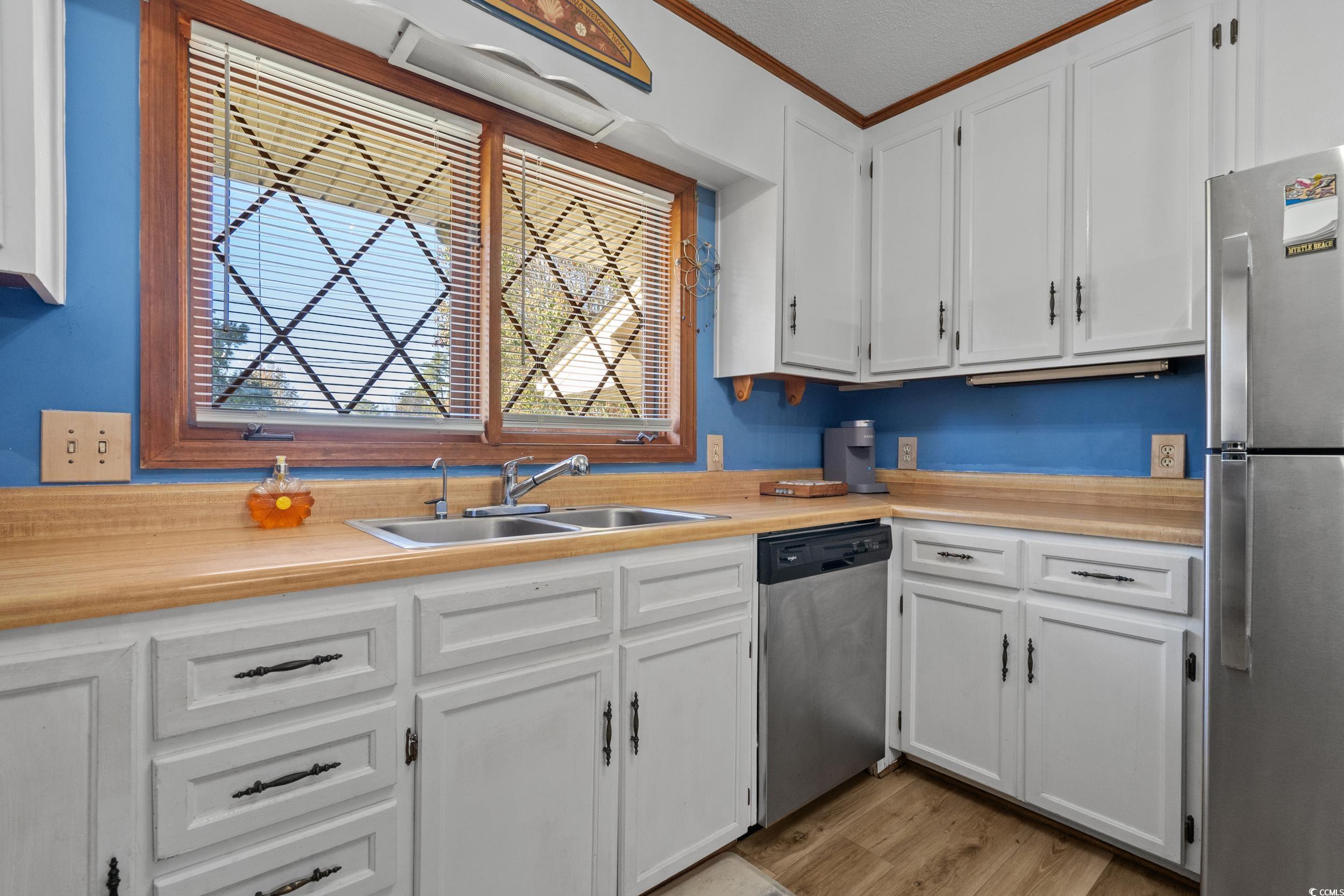1063 Burcale Road Myrtle Beach, SC 29579 - Photo 18 of 36 Kitchen featuring light countertops, white cabinets, appliances with stainless steel finishes, light wood-type flooring, and ornamental molding