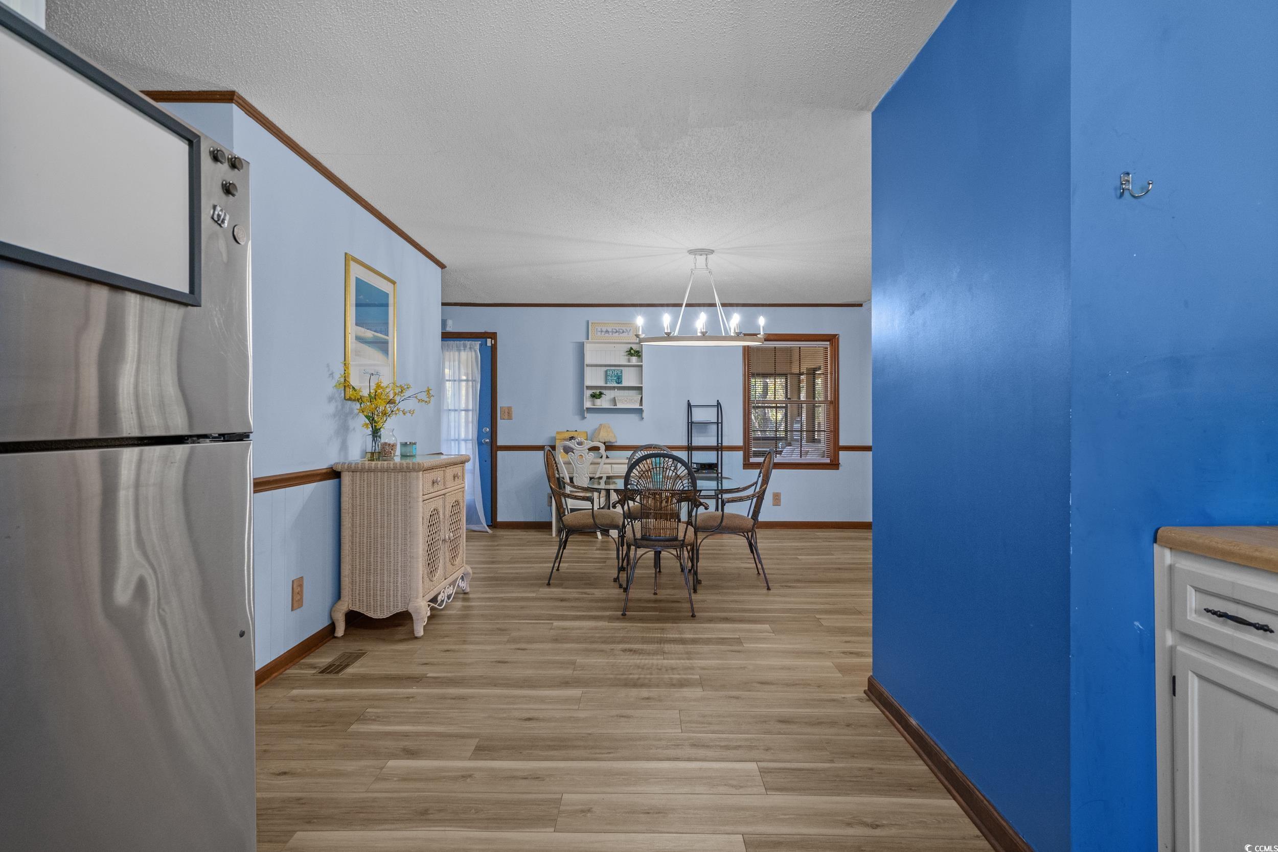1063 Burcale Road Myrtle Beach, SC 29579 - Photo 19 of 36 Dining area with light wood-style floors, ornamental molding, a textured ceiling, and a chandelier