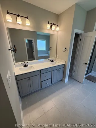 a spacious bathroom with a double vanity sink a large mirror and a bathtub
