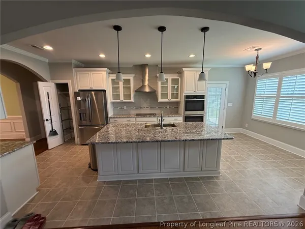 a kitchen with kitchen island granite countertop a refrigerator a oven a sink and a counter