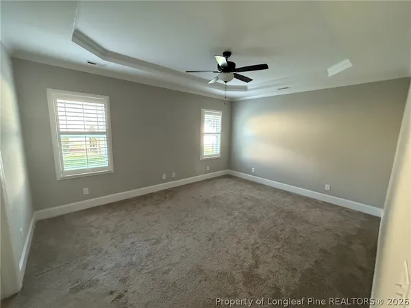 en empty room with windows and chandelier fan