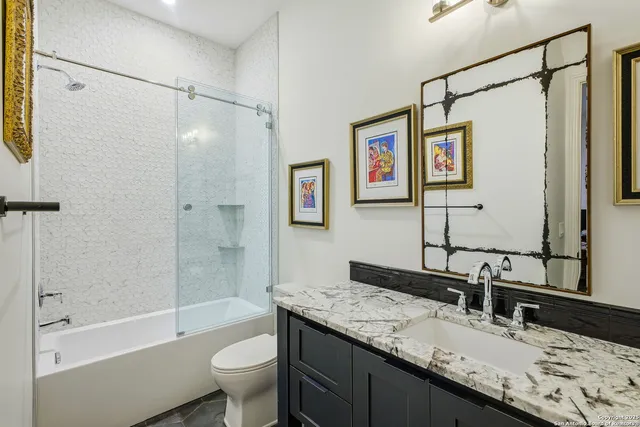a bathroom with a granite countertop toilet a sink and a mirror